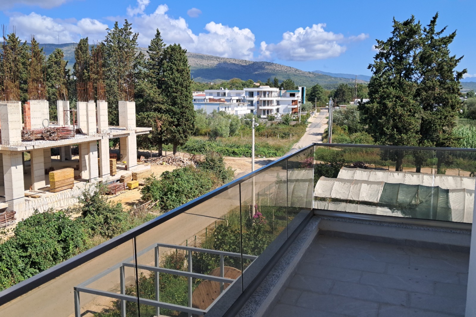 Stunning Ulcinj investment view: modern homes, lush greenery, mountain backdrop. Exclusive at immobilien.ekosphere.me by ekosphere doo.