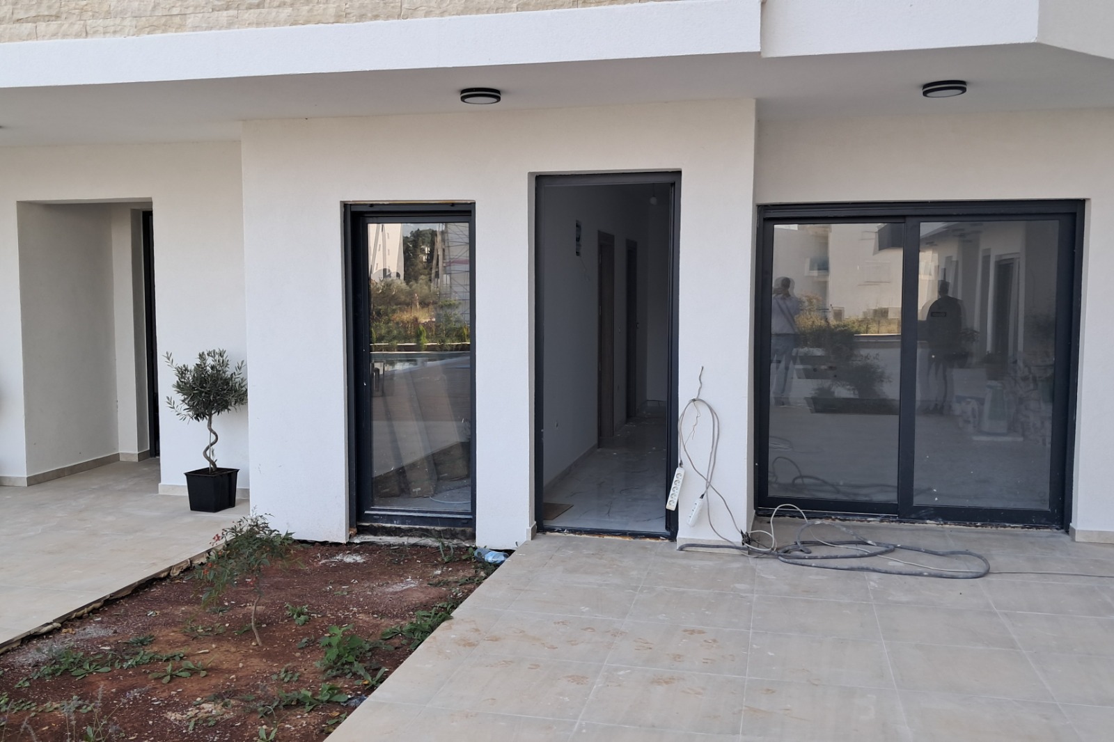 Modern Ulcinj property: sleek white-walled building with glass door, large window, open entry. Exclusive on immobilien.ekosphere.me by ekosphere doo.
